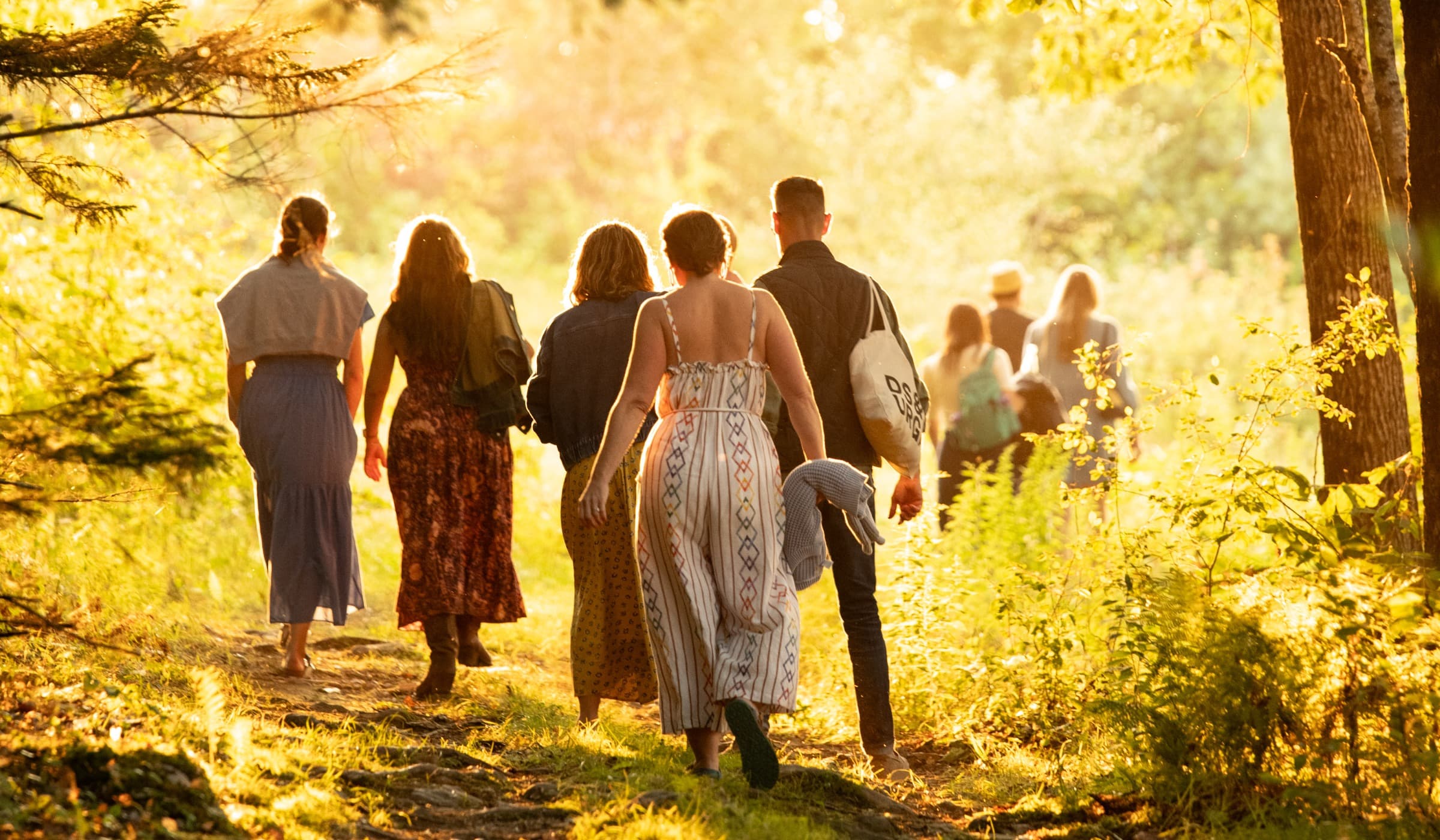 A group walking the field toward the barn, seen from behind.